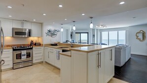 Een moderne keuken met witte kasten, roestvrijstalen apparatuur en een groot eiland.