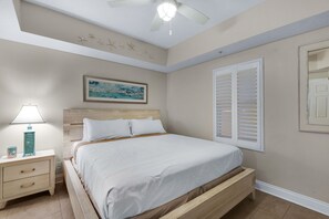 A bedroom with a bed, nightstand, lamp, and a painting on the wall. - AMAZING BEACH VIEWS FROM THE SPACIOUS GULF FRONT BALCONY! BEACH CHAIR SERVICE INCLUDED! SUPER CLEAN! WALK TO PIER PARK! (Panama City Beach)
