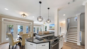 A modern kitchen with white cabinetry, a central island with a stove, and pendant lighting. - Casa Lontano - Luxury Home Near the Beach with Gulf Views & Shared Pool (Destin)
