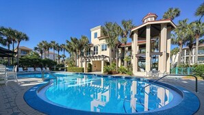 A swimming pool with a 3 FT depth marker, surrounded by palm trees and a building with a covered patio area. - Casa Lontano - Luxury Home Near the Beach with Gulf Views & Shared Pool (Destin)