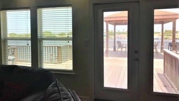 A room with a large sliding glass door leading to an outdoor deck with a view of a body of water. - South Harbor Condo. 3 Bedroom, 3 Bath. Boat Slip. LED Fishing Light. Large Deck. (Port Mansfield)