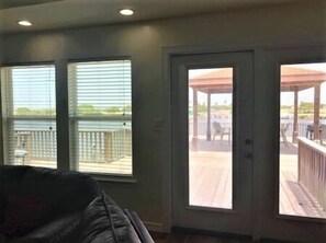 Een kamer met een grote schuifglazen deur die uitkomt op een terras met uitzicht op een wateroppervlak.