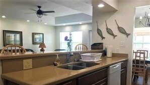 A kitchen with a wooden countertop, a sink, and cabinets. There are decorative fish on the wall and a ceiling fan. - South Harbor Condo. 3 Bedroom, 3 Bath. Boat Slip. LED Fishing Light. Large Deck. (Port Mansfield)