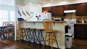 A kitchen with wooden cabinets, a white refrigerator, a stove, and a trash can. - South Harbor Condo. 3 Bedroom, 3 Bath. Boat Slip. LED Fishing Light. Large Deck. (Port Mansfield)