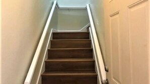 A staircase with wooden steps and white handrails, leading to a door with a silver handle. - South Harbor Condo. 3 Bedroom, 3 Bath. Boat Slip. LED Fishing Light. Large Deck. (Port Mansfield)