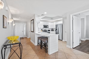 A modern kitchen with white cabinetry, a central island, and stainless steel appliances.