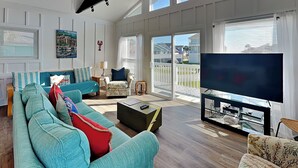 Amplia sala de estar con un sofá grande, un televisor y vistas al exterior.