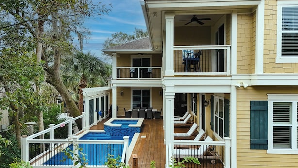 Ein zweistöckiges Haus mit Balkon, Pool und einer Terrassenfläche.