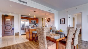 Una cocina moderna con electrodomésticos de acero inoxidable, un comedor con sillas de mimbre y vista al salón.
