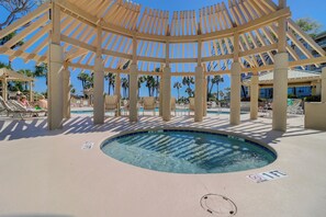 Zona de piscina con una piscina circular, sillas de descanso y una pérgola de madera.