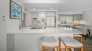 A modern kitchen with a central island, built-in appliances, and a dining area with a table and chairs. - Sundial P301 Vacation Rental on Sanibel Island (Sanibel)