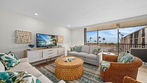 A modern living room with a large TV, comfortable seating, and a view of the beach. - Sundial P301 Vacation Rental on Sanibel Island (Sanibel)