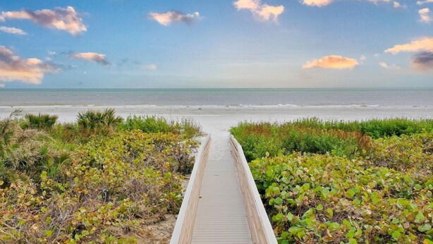 A wooden boardwalk leading to a beach with a clear sky and scattered clouds. - Sundial P301 Vacation Rental on Sanibel Island (Sanibel)