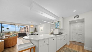 A modern kitchen with a large island, white cabinetry, and a view of the ocean. - Sundial P301 Vacation Rental on Sanibel Island (Sanibel)