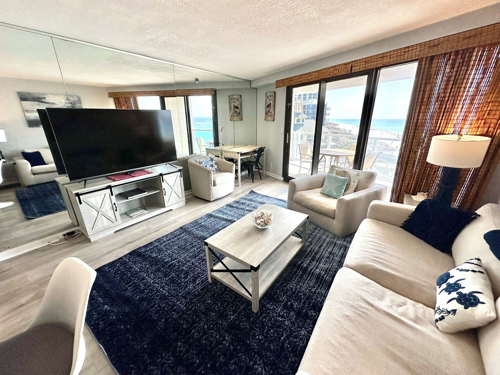 A modern living room with a flat-screen TV, a dining area, and large windows with a city view.