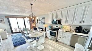 Una cocina moderna con armarios blancos, electrodomésticos de acero inoxidable y una zona de comedor con una mesa redonda y sillas.