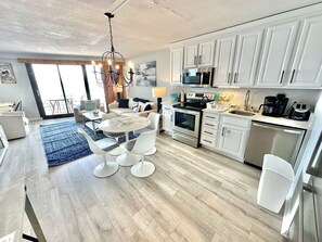 A modern kitchen with white cabinets, stainless steel appliances, and a dining area with a round table and chairs.