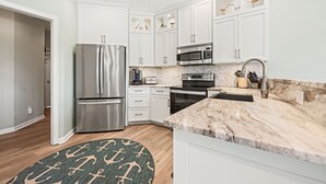 Una cocina moderna con armarios blancos, electrodomésticos de acero inoxidable y encimera de mármol.
