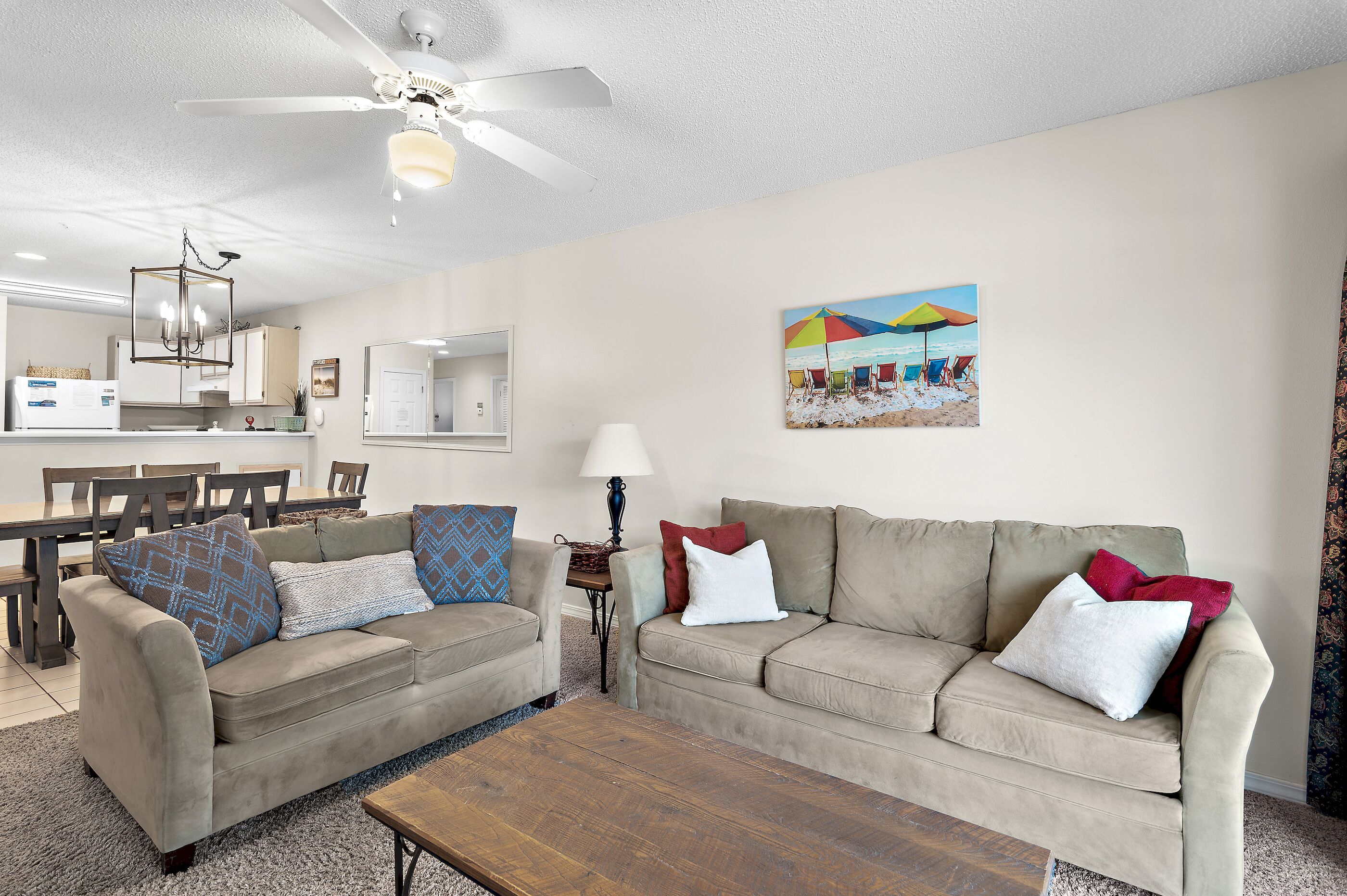 A living room with a beige sofa, a wooden coffee table, and a ceiling fan.