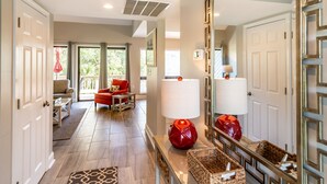 A spacious hallway with a large mirror, a red armchair, and a console table with decorative items.
