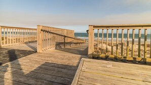 A wooden boardwalk leading to a beach with a clear view of the ocean.