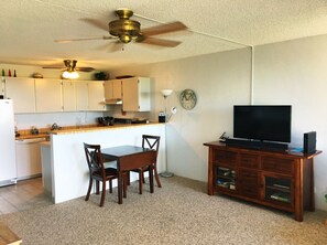 A compact living space with a kitchenette, dining area, and entertainment unit.