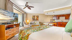A hotel room with a bed, a desk, a chair, a kitchenette, and a large window with a view of the beach. - Maui Resort Rentals: Honua Kai Hokulani 533 – Upgraded 5th Floor Oceanview Studio (Lahaina)