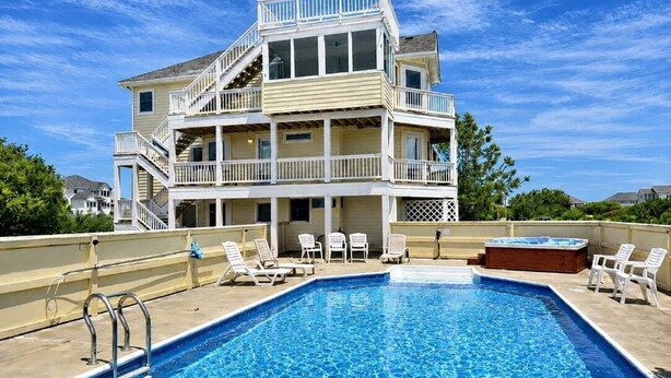 A two-story building with a pool, outdoor seating, and a hot tub.