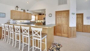 A kitchen with a central island, wooden cabinets, and white bar stools.