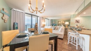 Ein modernes Wohnzimmer mit Essbereich, einer Chandelüster und einer Küche mit Barhocker.