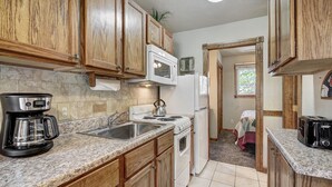 A compact kitchen with wooden cabinets, a microwave, a stove, and a coffee maker. - Cozy, Corner Top Floor Unit in Perfect Downtown Location | PM8B (Breckenridge)