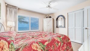 Een slaapkamer met een bed, een plafondventilator, een kledingkast en een raam met uitzicht.