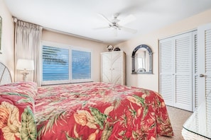 A bedroom with a bed, a ceiling fan, a wardrobe, and a window with a view. - Kihei Beach #409 – Immersive Views and Tranquil Escape (Kihei, Maui)