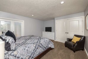 A bedroom with a bed, a chair, a television, and a wardrobe.
