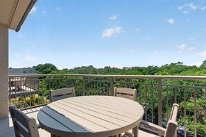 A balcony with a round table and chairs, overlooking a lush green landscape.