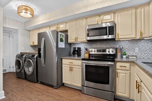 A modern kitchen with stainless steel appliances, wooden cabinets, and a tiled backsplash.