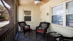 A porch with two wicker chairs, a small table, and a window. - Millican North - B 2 bedrooms, 2 bathrooms (Jekyll Island)