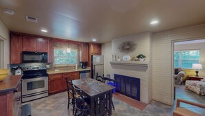 A kitchen with wooden cabinets, a microwave, stove, and a dining area with a table and chairs. - Millican North - B 2 bedrooms, 2 bathrooms (Jekyll Island)