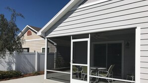 A house with a covered patio area featuring a table and chairs. - Walking distance to Lake Sumter Landing! Small Dog Friendly Villa w/Golf Cart (The Villages)
