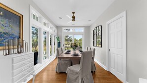 Uma área de refeições com uma mesa grande, cadeiras e um ventilador de teto.