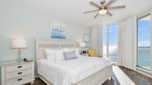 A bedroom with a large bed, a ceiling fan, and a view of the ocean through large windows. - Serene Modern Beachfront Condo w/ Easy Beach Access at Silver Beach Towers! 🌊☀ (Destin)