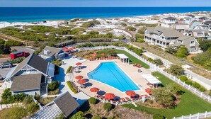 An aerial view of a resort with a large swimming pool, beach access, and ocean views.