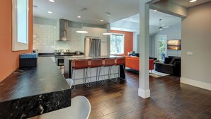 A modern kitchen with a central island, bar stools, and a dining area. - 5 Heron- Great Family Retreat. 363 Yard walk to the Beach! (Hilton Head Island)