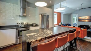 A modern kitchen with a marble island, stainless steel appliances, and orange bar stools. - 5 Heron- Great Family Retreat. 363 Yard walk to the Beach! (Hilton Head Island)