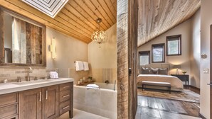 Een moderne badkamer met een grote spiegel, houten kastjes en een bad.