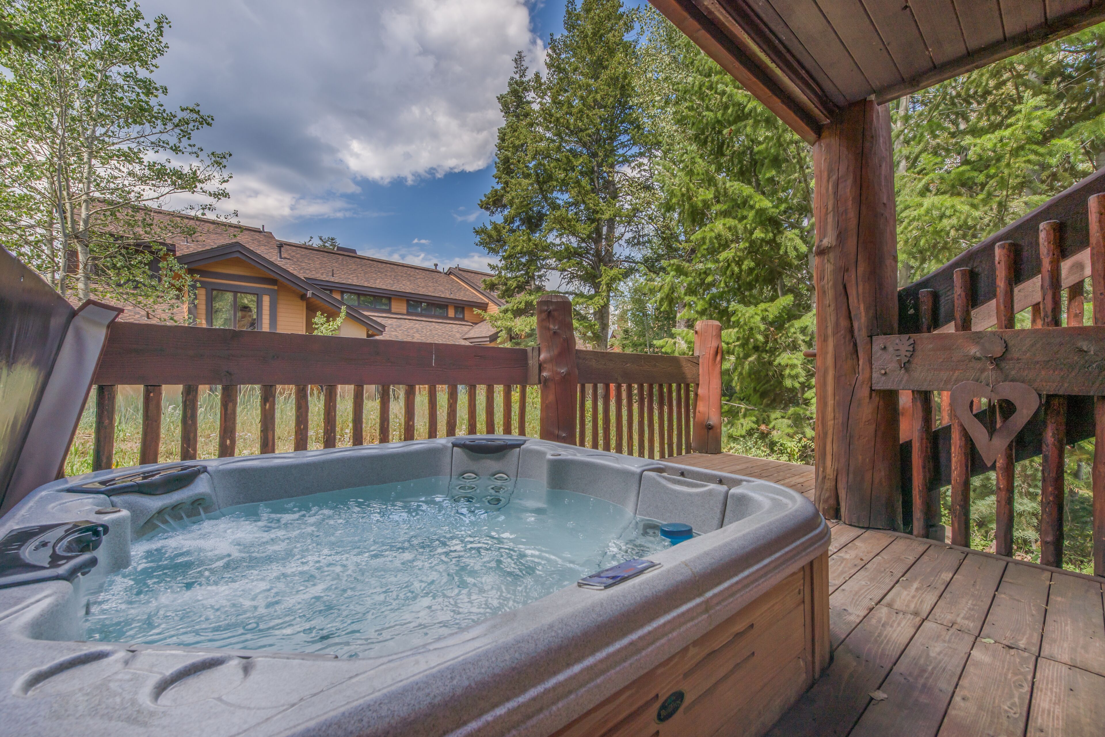 A hot tub on a wooden deck with a wooden fence and trees in the background.