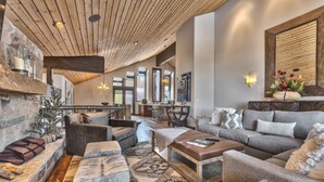 Een ruime woonkamer met een stenen openhaard, moderne banken en een groot raam met uitzicht op het interieur.