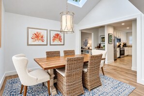 A dining area with a wooden table, wicker chairs, and a hanging light fixture.