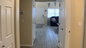 A hallway with a wooden floor, white doors, and a ceiling light. - Home Field Advantage by Mesquite Vacation Rentals with Community Pool and $510 in free daily activities (Mesquite)