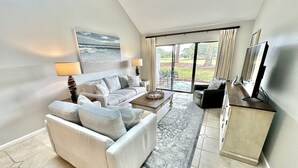 A modern living room with a sofa, coffee table, and a television on a cabinet.